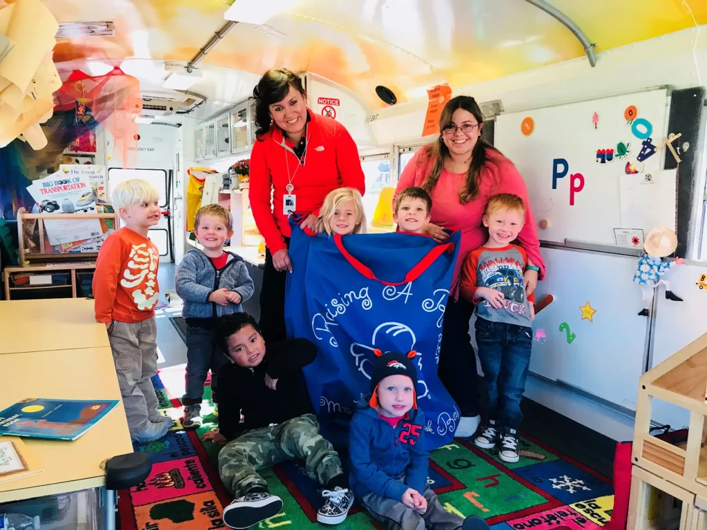 Seven children and two teachers inside the mobile preschool bus