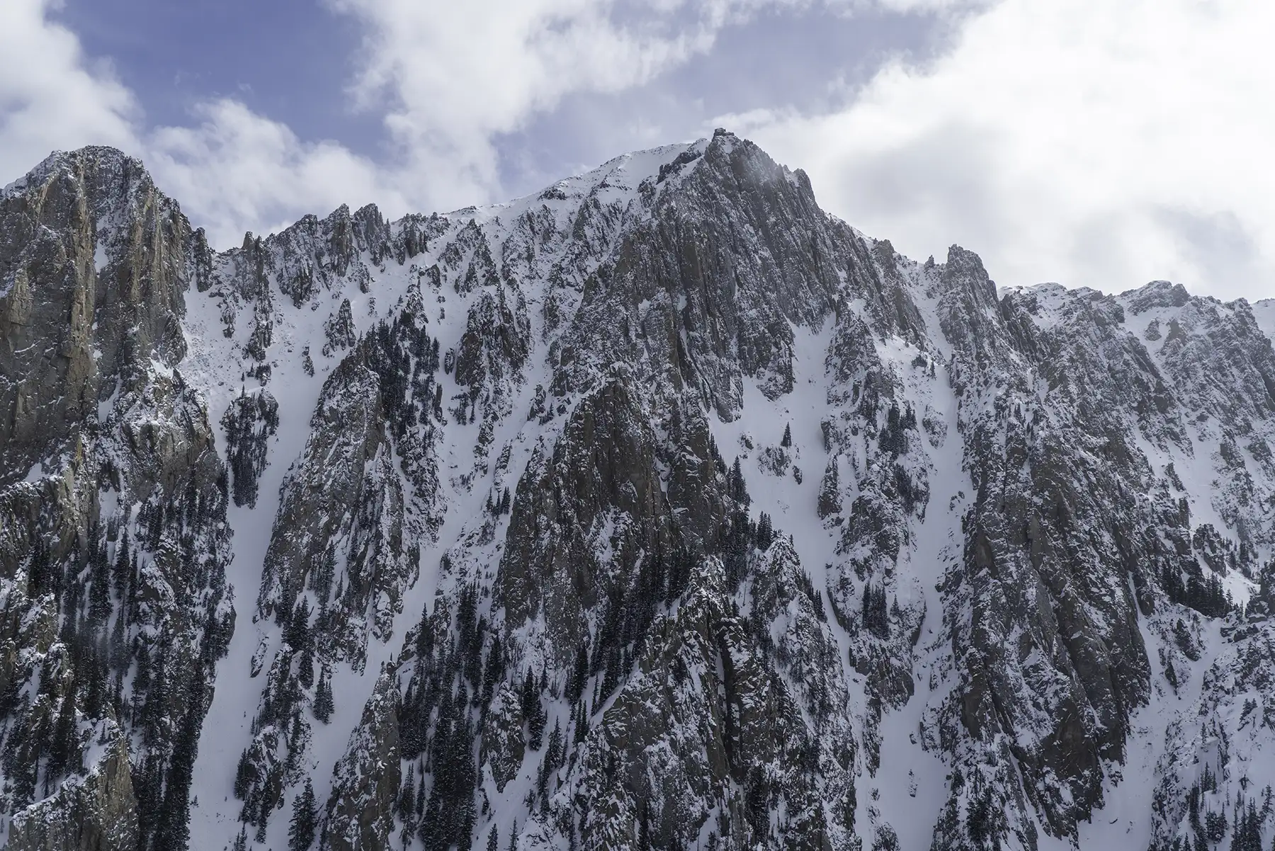 A wide shot of a mountain range in Aspen, Colorado, during a partly cloudy day.