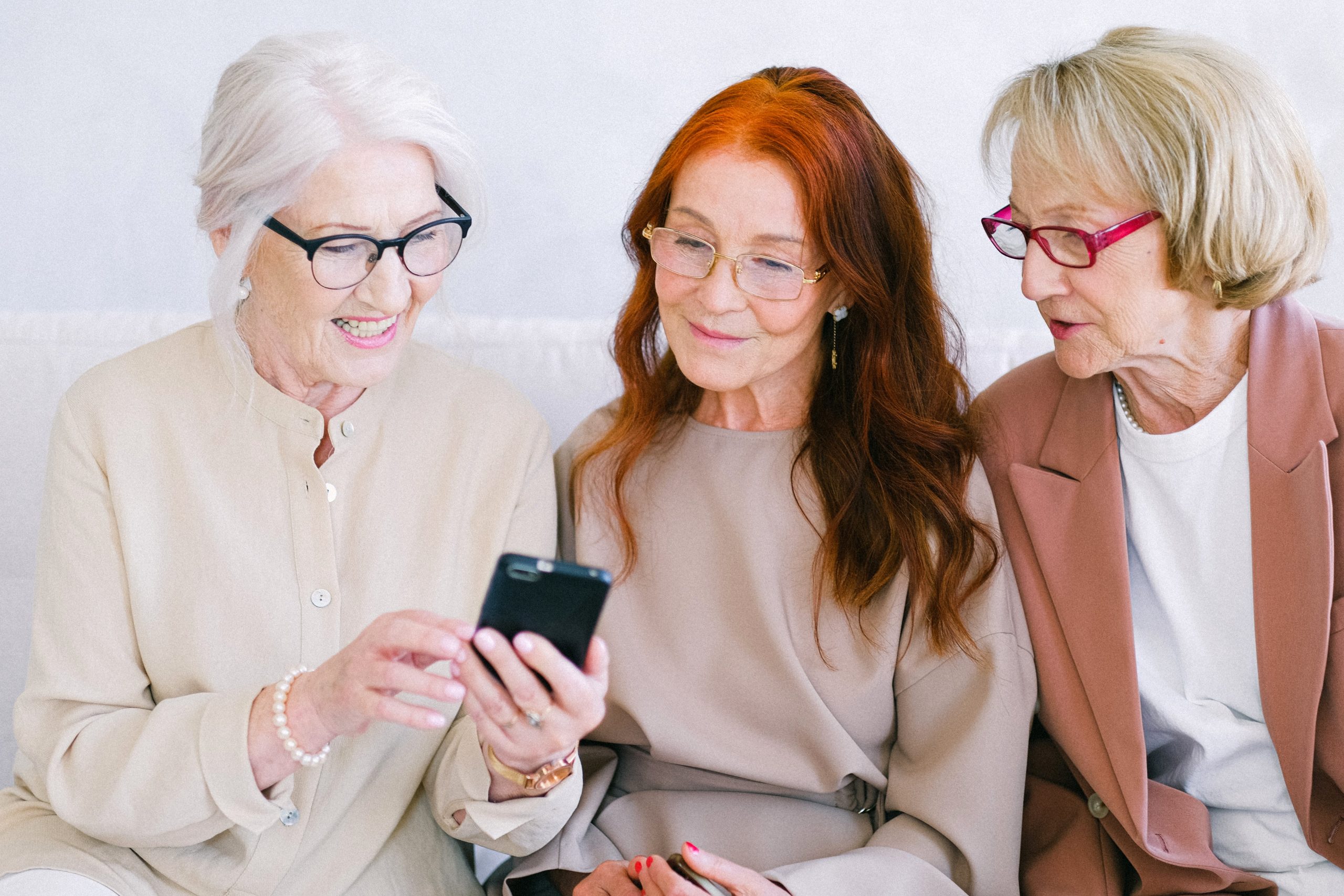 Three white women looking at a cell phone|