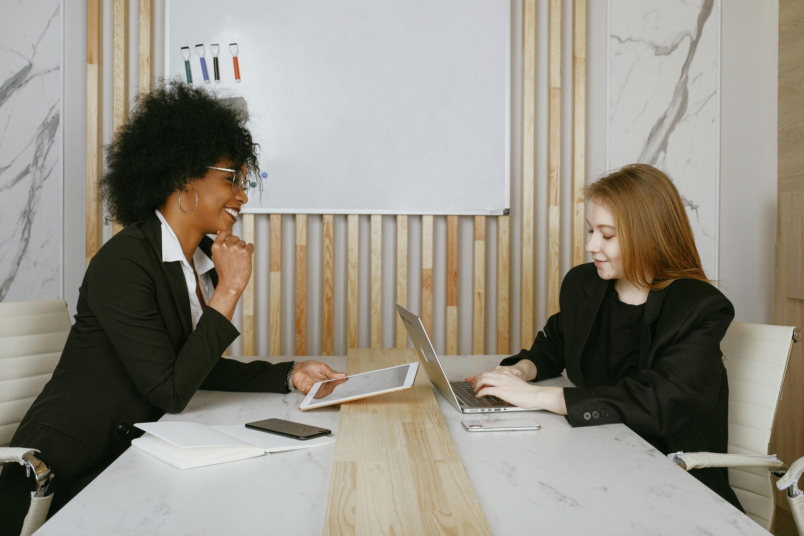 Two women working on a laptop and tablet