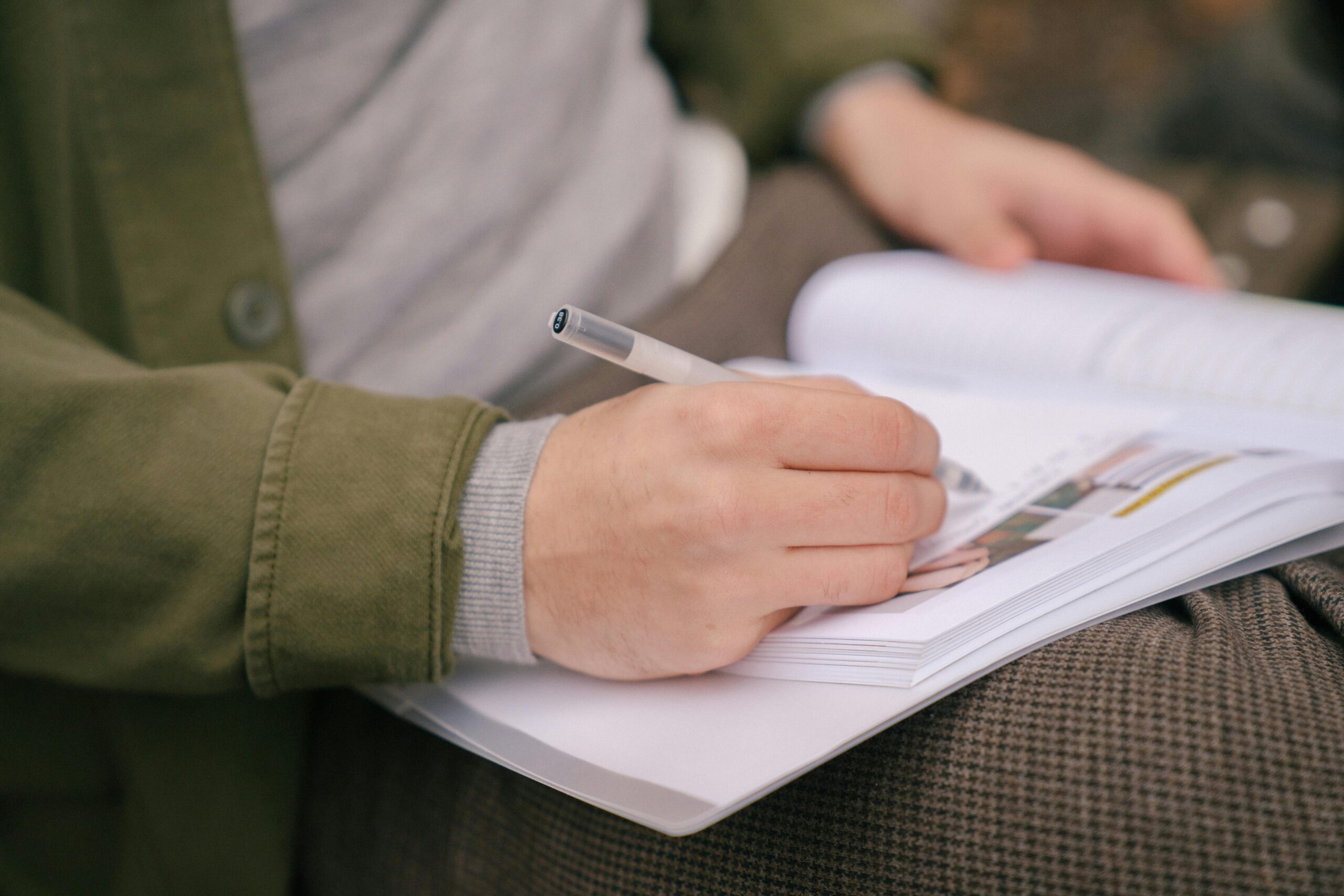 Person using a pen to write in a book