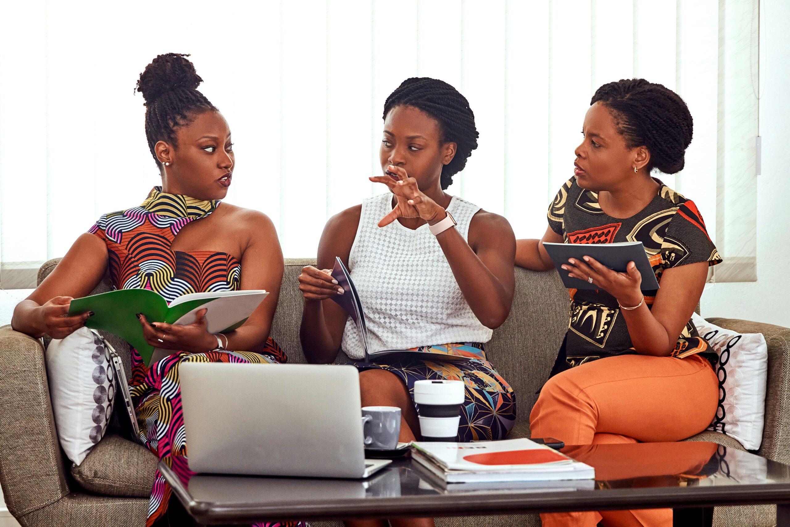 Three people talking to each other around a computer